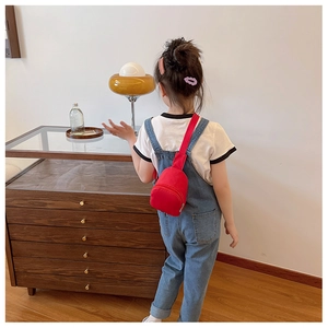 Detailed view of child wearing a mini red canvas crossbody chest bag for daily fashion
