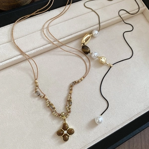 Close-up of tiger eye clover pendant and pearl bead necklace with gold metal chain
