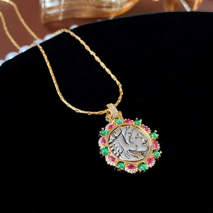Macro shot of gold portrait medallion necklace with red, green gems and crystals