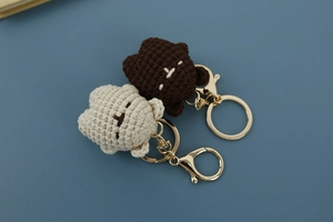Detail of handmade crochet bear keychains in brown and beige with gold metal clips