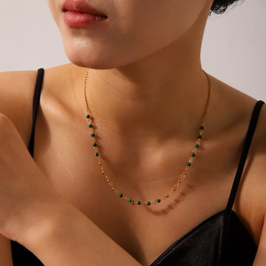 Close-up of 18K gold plated necklace with green beads and sun star charms on model