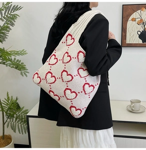 Texture de tricot détaillée d'un sac à bandoulière blanc avec des motifs de cœurs rouges en 3D