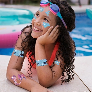 Girl at pool wearing glitter mermaid fish scale temporary tattoos and a purple mermaid tail