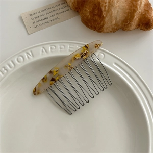 Tortoiseshell acetate hair comb with black metal teeth shown in an aesthetic lifestyle setting