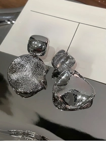 Vue macro de boucles d'oreilles argentées avec clous carrés et pendentifs ronds texturés
