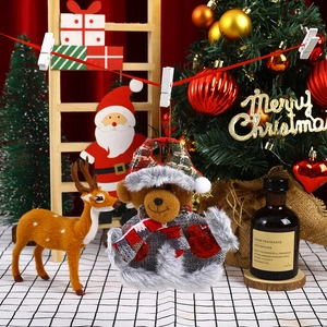 Detail of Christmas plush bear ornament with red plaid hat hanging on a festive tree