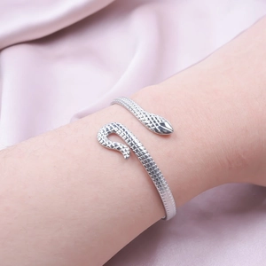 Detailed close-up of a silver C-shaped snake scale bracelet on a female wrist