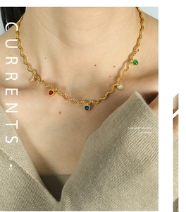 Detail of gold wave chain necklace featuring five colorful heart-shaped gemstones for women