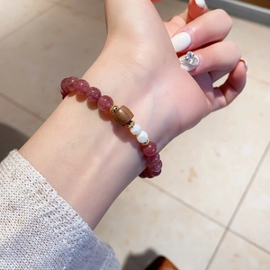 Detail eines Perlenarmbands mit Erdbeerquarz, Holzperlen und Perlen am Handgelenk