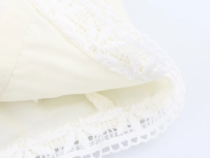 Detailed close-up of delicate white lace trim on a cream-colored puffy sleeve shirt