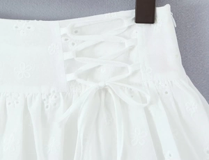 Detail of white corset lace-up waist with hollow embroidery and eyelet lace texture