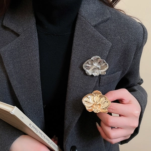 Close-up of orchid flower brooch with detailed metallic petals on a dark suit
