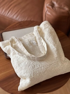 Macro view of detailed floral lace embroidery on off-white cotton tote bag fabric