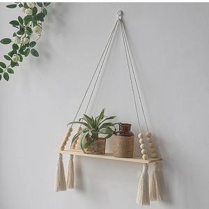 Detail of macrame wall hanging shelf with wood beads, fringe and pine wood board