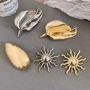 Close-up of metallic sun and leaf brooches in gold and silver with polished mirror finish