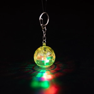 Luminous disco ball keychain with LED light projecting colorful shadows on black background