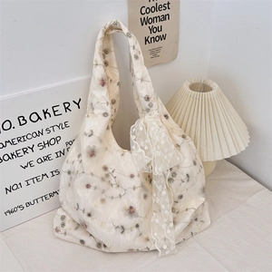 Close-up of floral embroidery on cream canvas tote bag with a lace bow detail