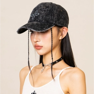 Close-up of distressed black denim baseball cap with butterfly embroidery and frayed edges