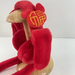 Red plush winter earmuffs featuring festive gold Fu character embroidery on display
