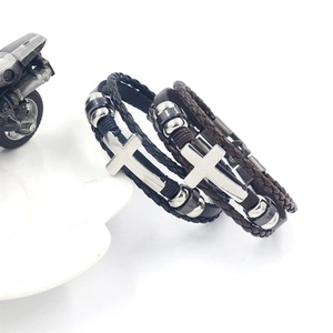 Detail of multilayer woven leather bracelets with silver cross charms in black and brown