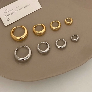 Minimalist gold and silver hoop earrings in four sizes displayed on a ceramic tray