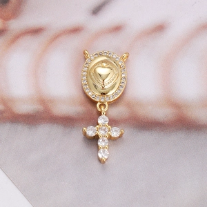 Detail of 18K gold-plated oval pendant with zircons and hanging cross on shell base