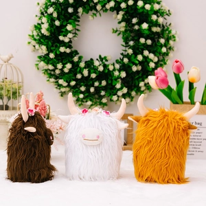 Three plush Scottish Highland Cows in brown, white, and gold colors with floral accents