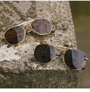 Close-up of polarized aviator sunglasses with gold metal frames on natural stone