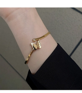 Detailed view of an 18k gold butterfly open cuff bracelet with frosted wings and zircon
