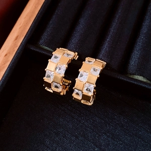 Gros plan de créoles plaquées or 18k avec motif damier et zircons incrustés