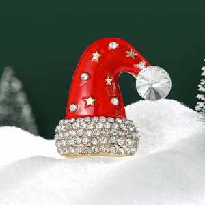 Detailed close-up of a red enamel Christmas hat brooch with white rhinestones on snow
