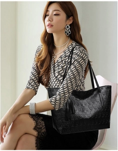 Close-up of black tote bag featuring embossed skull pattern and tassel detail
