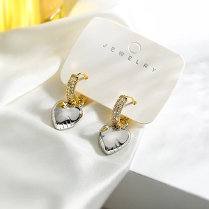 Detailed close-up of heart charm earrings with crystal inlays on soft silk background