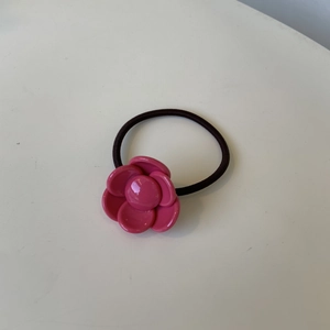 Detail of a pink camellia resin flower charm on a black elastic ponytail holder