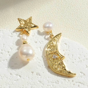 Detail of asymmetric freshwater pearl earrings with 14K gold sun and moon facial carvings