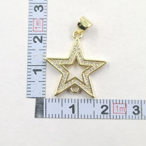 Détail du pendentif étoile dorée avec zircons montrant les dimensions sur une règle