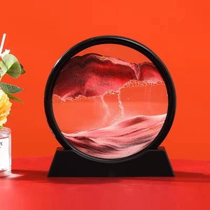 Close-up of a circular sand art piece with red and black sand in a glass frame