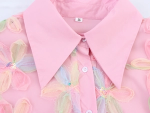 Close-up of pink puff sleeve shirt featuring floral embroidery and sequin collar detail