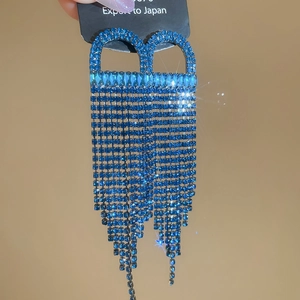 Detailed view of luxury blue rhinestone fringe drop earrings with sparkling star effect