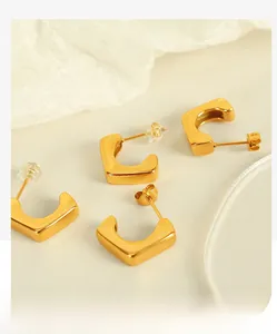 Detail view of 18k gold-plated geometric C-shaped stud earrings with matte metal finish