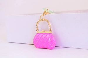 Detailed close-up of a pink quilted handbag keychain with golden hardware on white background