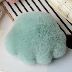 Close-up of fluffy mint green rex rabbit fur cat paw charm with soft plush texture