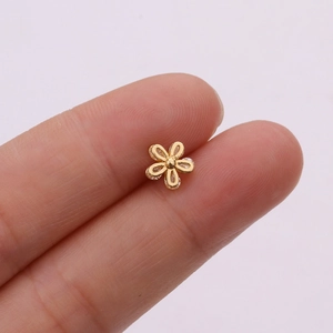 Macro view of a tiny rose gold flower stud earring with zircon inlay held by fingers