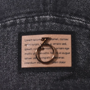 Macro detail of dark washed denim cap with vintage leather patch and golden metal hardware
