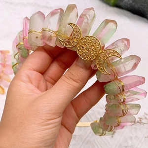 Detail of pink and green crystal crown with golden triple moon symbol on a metal headband