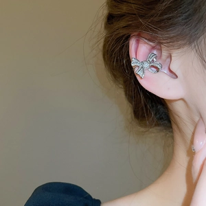 Close-up of sparkling bow-shaped silver ear cuff with inlaid crystals on model's ear