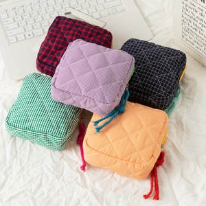 Quilted checkered makeup bags in five colors stacked on a white minimalist background