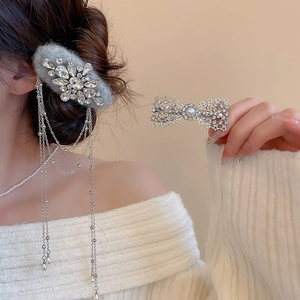 Detailed view of silver bow hair clip with rhinestones, pearls and velvet fringe