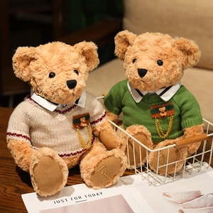 Pair of brown curly plush teddy bears in knitted sweaters inside a white metal basket