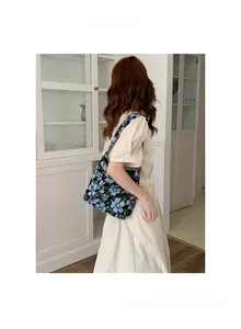 Floral embroidery underarm bag styled with a beige dress in a bright interior setting